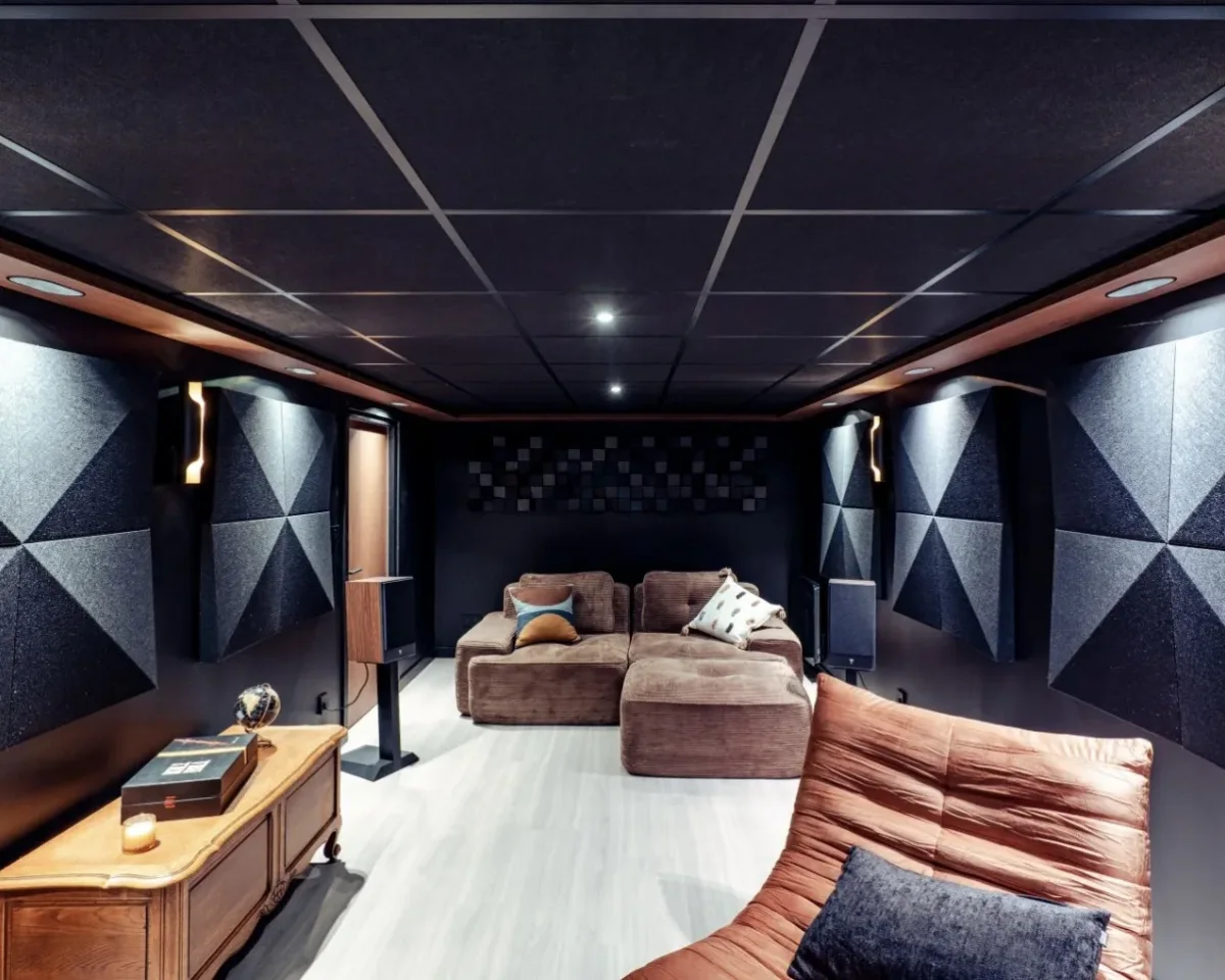 Salle de cinéma dans le Pays de Gex, vue vers le canapé d'angle sous le faux plafond en dalles noires, chantier ECP mis en avant sur la page d'accueil